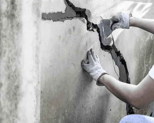 Technician sealing a structural crack in a residential concrete foundation wall