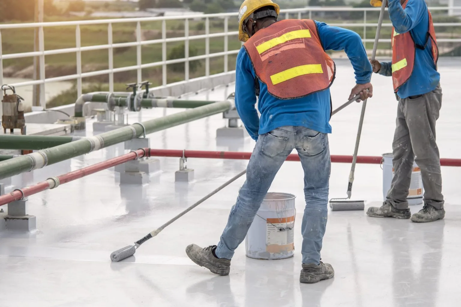 Contractor spray-applying a waterproofing membrane to an exterior foundation wall